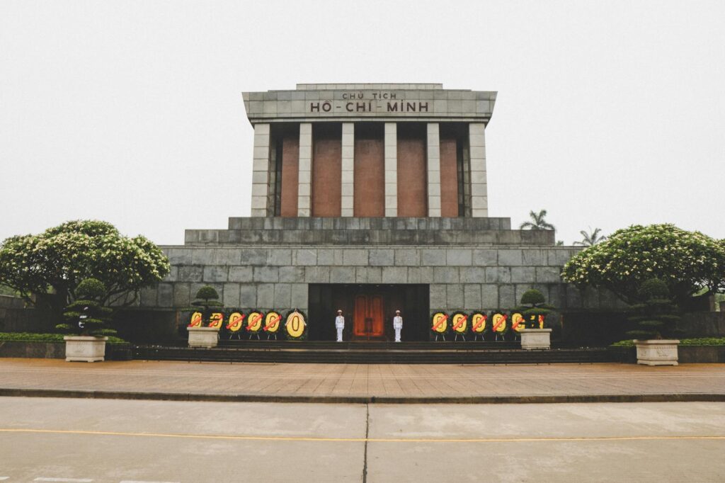 Front view of the iconic Ho Chi Minh Mausoleum in Hanoi, Vietnam with guards and floral wreaths.