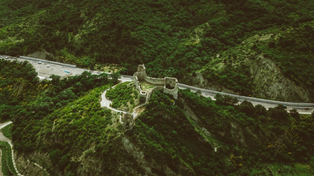 Stunning aerial view of an ancient fortress surrounded by lush hills in Georgia.