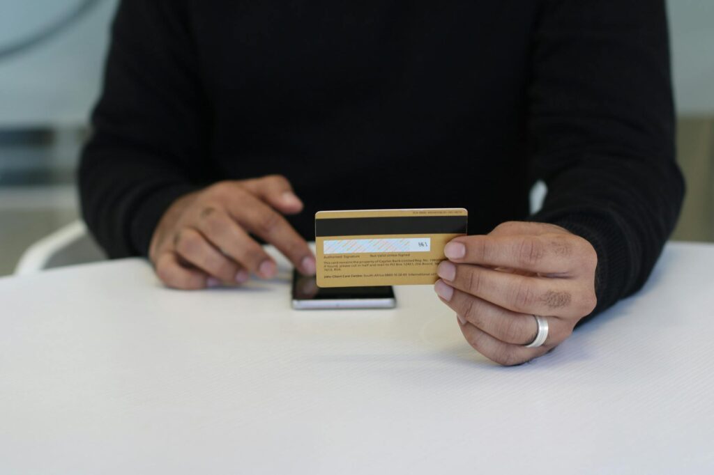 Person holding a credit card and smartphone, indoor close-up view.