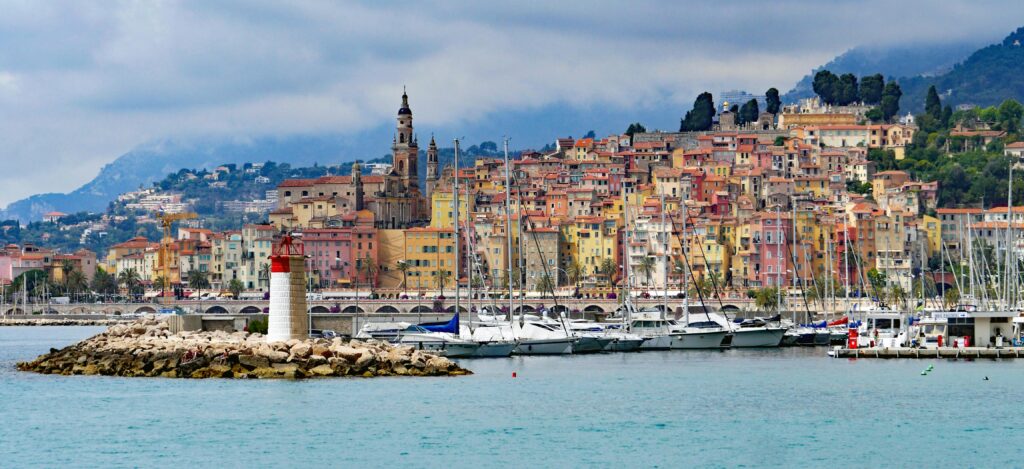 View of Menton's vibrant waterfront, featuring colorful houses and a scenic lighthouse.