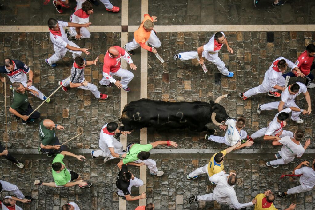 Top view of participants running with a bull during a vibrant street festival.