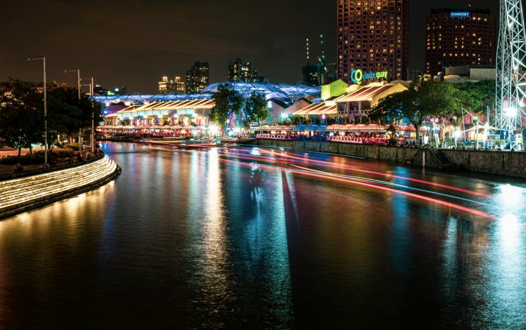 Vibrant night shot of Clarke Quay in Singapore reflecting colorful lights on the river.