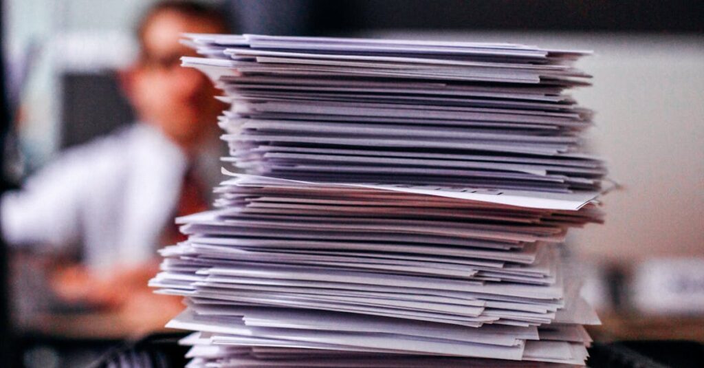 Pile of papers with 'Accepted' label in a busy office setting, highlighting information management.