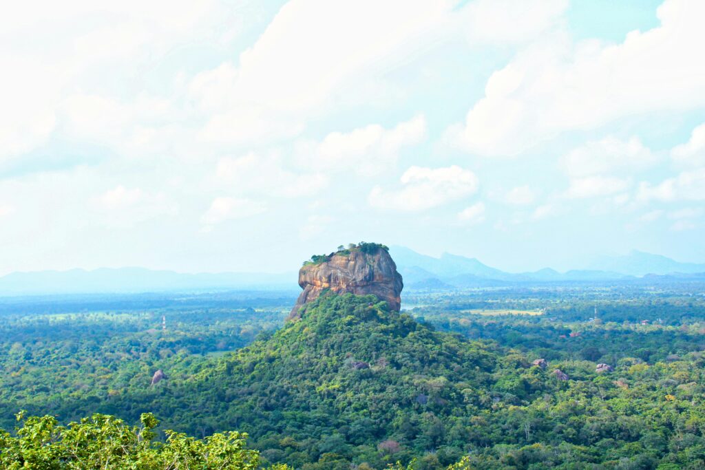 A breathtaking view of Sigiriya Rock surrounded by lush greenery under a blue sky in Sri Lanka.